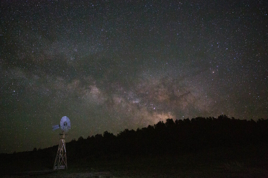 Milky Way over silhouette of windmill and trees.