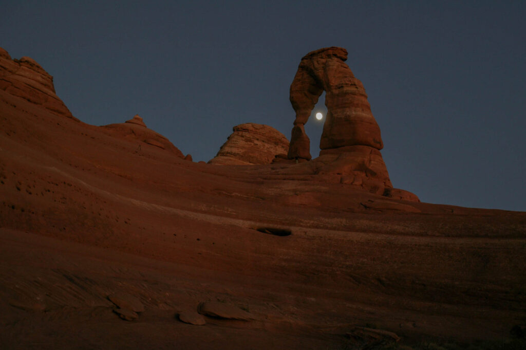 Full moon through Delicate Arch at nightfall.