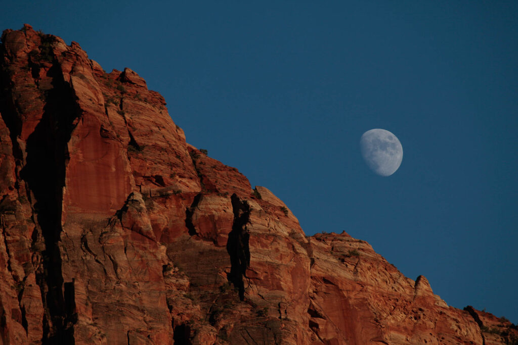 Red rock cliff under moonlit sky