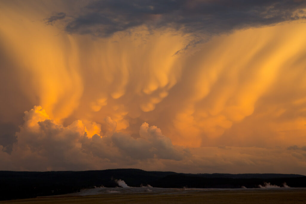 Orange mammatus clouds over landscape at sunset