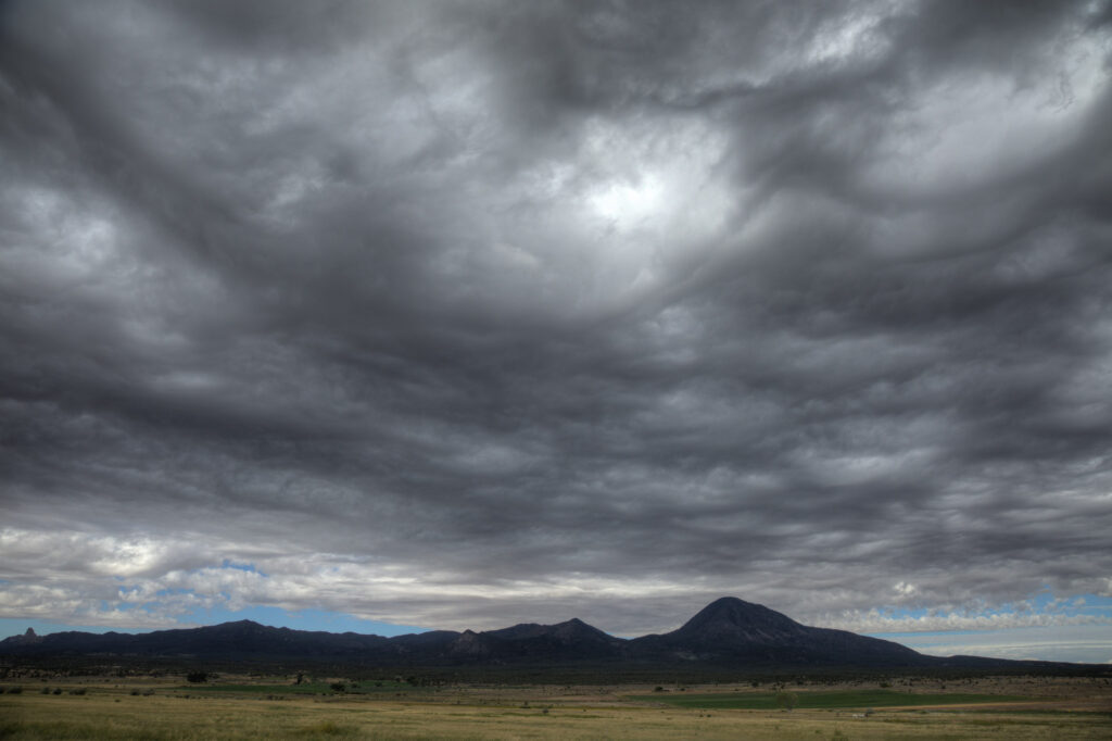 Dramatic clouds over mountainous landscape and grassland.