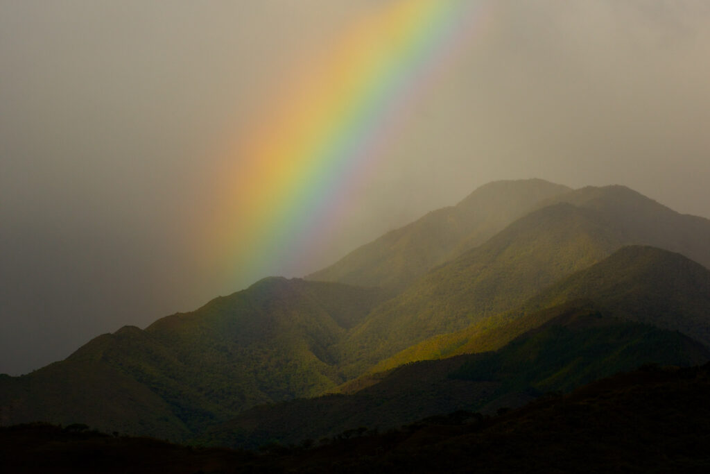 Colorful rainbow over lush green mountains.