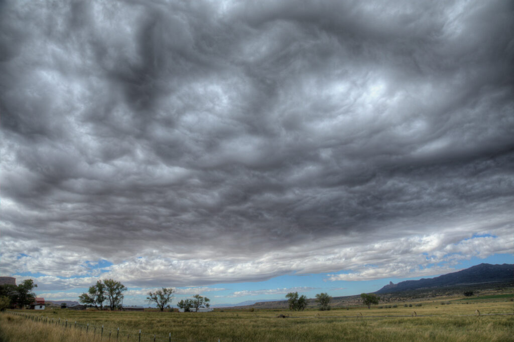 Cloudy sky over open grassy field.