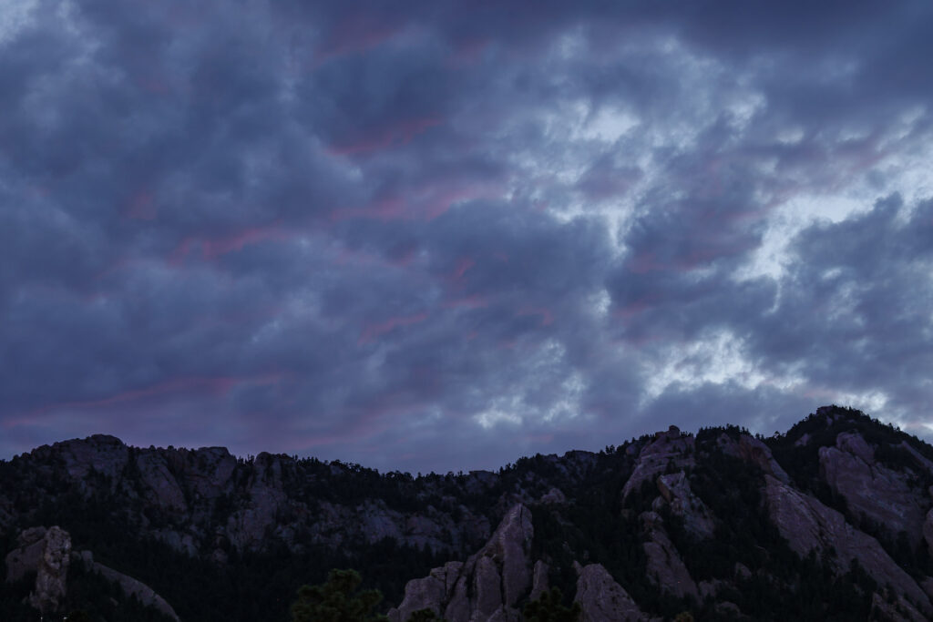 Rocky mountains under cloudy sky at dusk.