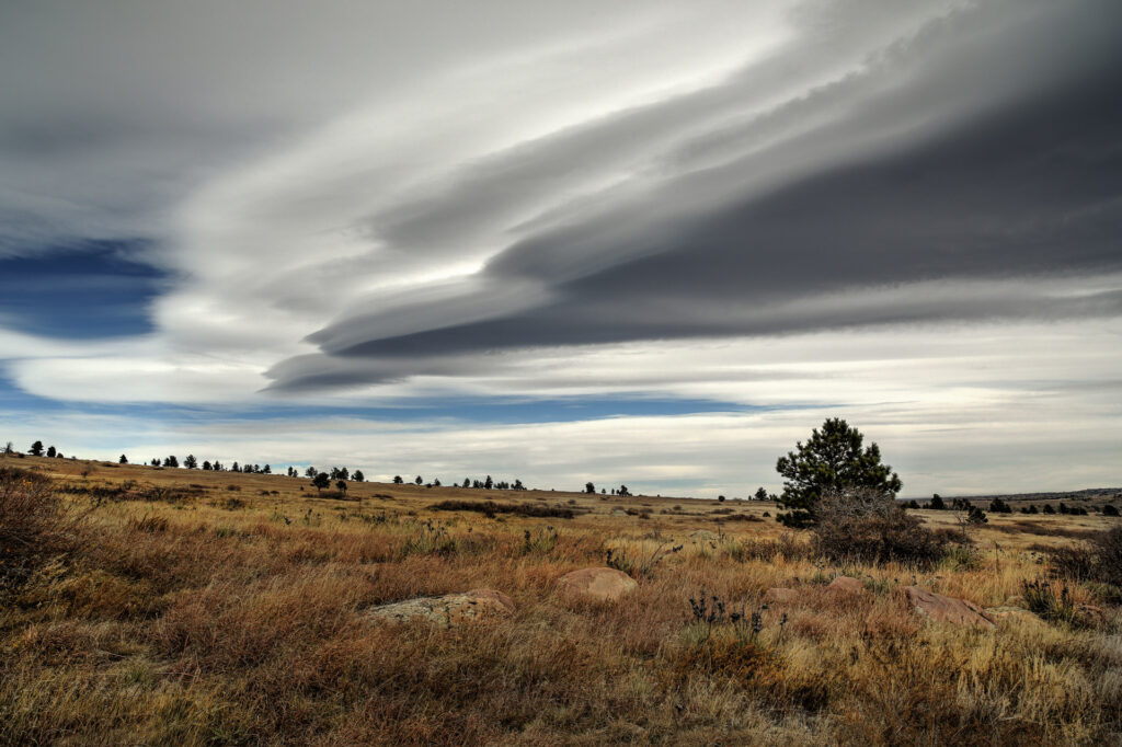 Cloudy sky over dry grassy landscape.